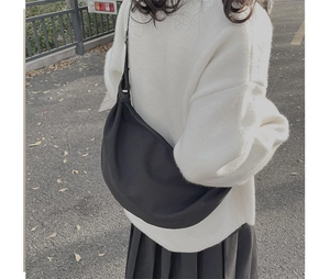Detail view of large black crescent shoulder bag shown worn crossbody style on a model