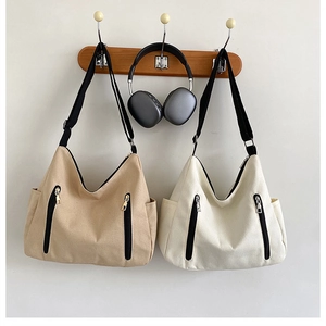 Détails des grands sacs cabas en toile kaki et blanc crème sur crochets muraux