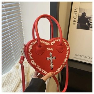 Detail of red heart-shaped leather bag featuring white Baby script and cross print