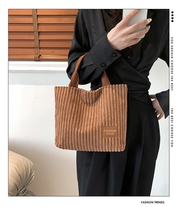 Close-up of brown corduroy tote bag featuring vertical texture and fashion logo label