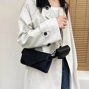 Minimalist black chain shoulder bag set on white coat with elegant matte finish