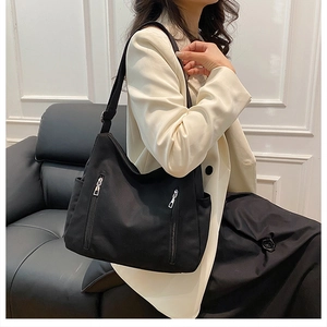 Détail d'un sac cabas noir en nylon avec fermetures métalliques et bandoulière large