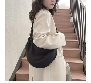 Detail of a black minimalist half-moon crossbody bag with an adjustable wide strap