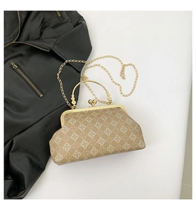 Dettaglio di una borsa a conchiglia vintage beige con motivo a quadrifoglio