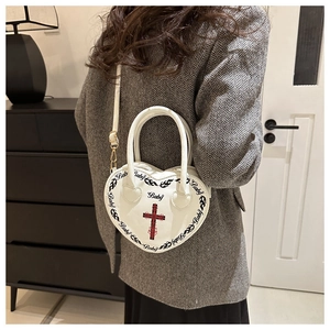 Detail shot of heart-shaped handbag with gothic cross, fire patterns and Baby lettering
