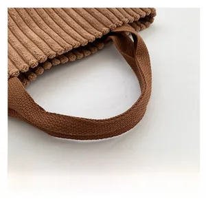 Detailed close-up of caramel brown corduroy fabric and durable reinforced strap handles