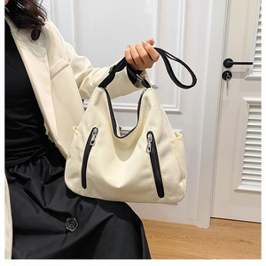 Détail du grand sac cabas en toile crème avec fermetures éclair noires décoratives