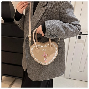 Detailed macro view of beige heart bag with Baby text and red cross on a grey blazer