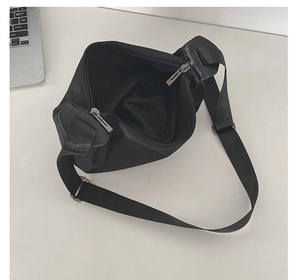 Detail view of black nylon shoulder bag with adjustable strap and dual zipper closure