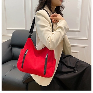 Détail d'un sac cabas en toile rouge vif avec fermetures éclair et bandoulières