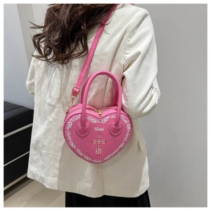 Rear view of model wearing pink heart-shaped bag with Baby print and cross detail