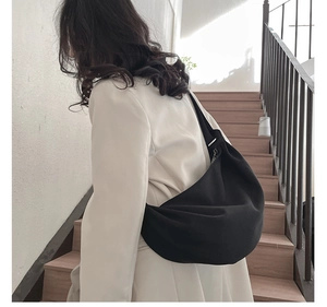 Minimalist black large hobo bag shown in use on a wooden staircase background