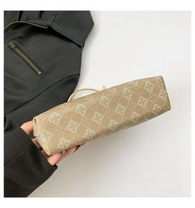 Dettaglio della base della borsa beige trapuntata con motivo floreale e manico in metallo oro