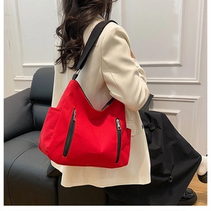Détail d'un grand sac bandoulière rouge en nylon avec deux fermetures éclair noires devant