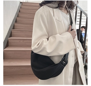 Minimalist black crescent crossbody bag shown on model for a sleek casual commute look