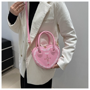 Close-up of heart-shaped pink crossbody bag with 'Baby' print worn with white blazer