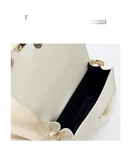 Detail view of white pleated handbag showing magnetic closure and golden hardware