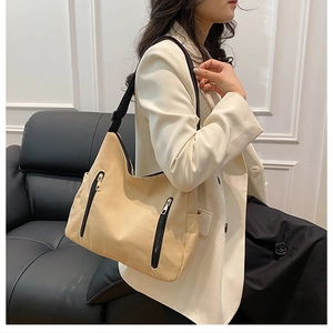 Vue détaillée d'un sac cabas en toile beige avec zips noirs et bandoulières en tissu