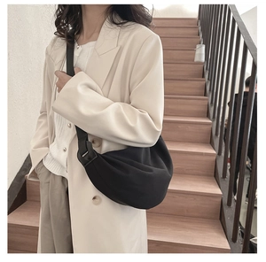 Model wearing a black crescent shoulder bag with an adjustable strap in a casual style