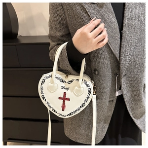 Detail showing the white heart-shaped bag with Baby print and cross on gothic style handbag