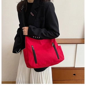 Détail du sac fourre-tout en toile rouge avec zips métalliques et poches latérales