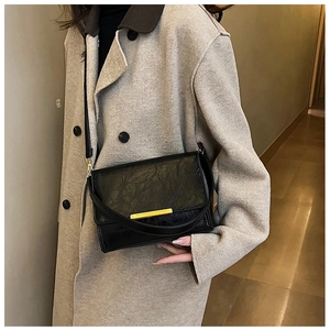 Detail view of black rectangular crossbody bag with pleated texture and gold metal clasp