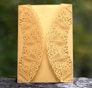 Close-up of golden laser-cut wedding invitation with intricate floral lace pattern