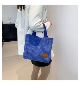 Detail of navy blue corduroy tote bag showing the texture and leather fashion label