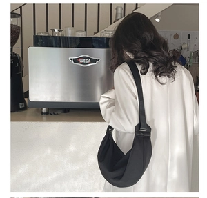 Minimalist black crescent hobo bag with wide shoulder strap shown in a lifestyle setting