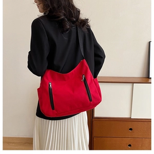 Détail du sac cabas en toile rouge avec fermetures éclair noires et poches latérales