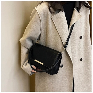 Detail of black crossbody bag with pleated texture and gold metal hardware on model
