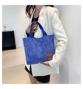 Detail of blue corduroy tote bag showing the brown leather label and soft ribbed texture