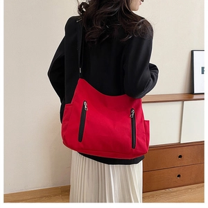 Détail du sac fourre-tout en toile rouge avec fermetures éclair noires et poches latérales