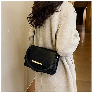 Classic black leather crossbody bag with gold metal trim shown on light grey coat