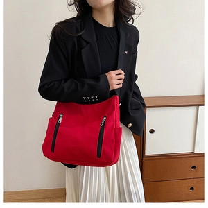 Détail du sac fourre-tout rouge en toile avec double fermeture éclair et bandoulière noire
