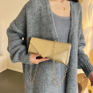 Detail of champagne gold envelope clutch with metallic texture and thick gold chain strap