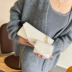 Detail of white envelope clutch set with texture leather and golden metal chain strap
