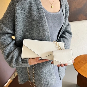 Close-up of white leather envelope bag set with golden chain strap for women