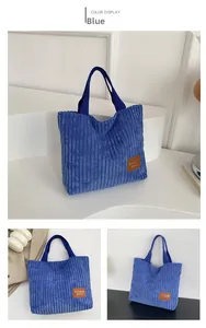Detail of blue corduroy tote bag showing vertical texture and brown leather logo tag