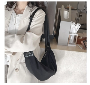 Detail view of the black crescent hobo bag with adjustable strap worn on the shoulder