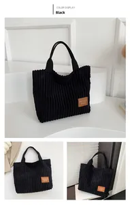 Detail of black corduroy tote bag showing vertical ribbed texture and brown leather tag