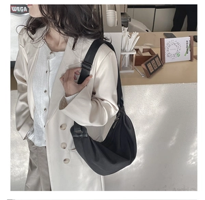 Detail of a minimalist black half-moon shoulder bag with an adjustable wide strap