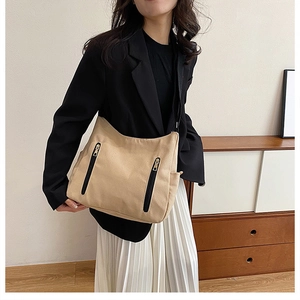 Vue détaillée du sac cabas en toile beige avec poches zippées noires porté par un mannequin