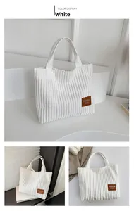 Detailed view of white corduroy tote bag showing vertical texture and brown leather label