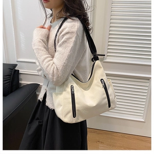 Détail d'un grand sac cabas en toile beige avec sangles noires et fermetures éclair