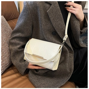 Close-up of minimalist cream crossbody bag with sleek gold bar and leather texture