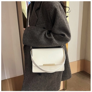 Detail view of a white PU leather crossbody bag with a sleek gold metal bar on the flap