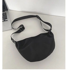 Detail view of a black crescent crossbody bag with adjustable wide canvas shoulder strap