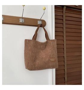 Detail of brown corduroy tote bag showing ribbed texture and fashion leather patch