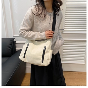 Détail du grand sac hobo en toile crème avec fermetures éclair noires et bandoulière